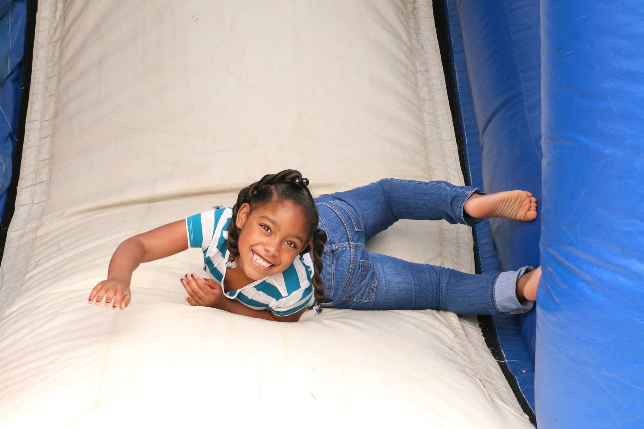 Young girl smiling on a bounce house slide at Hour of Power
