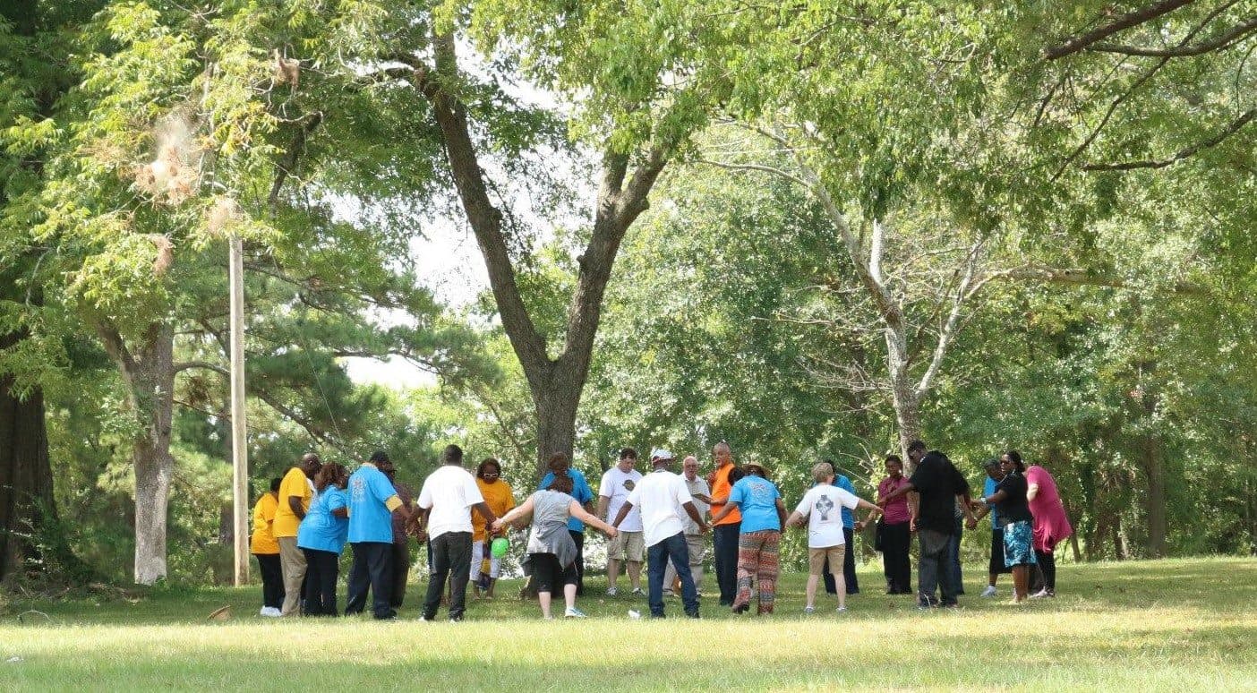 Community members holding hands in a circle outdoors